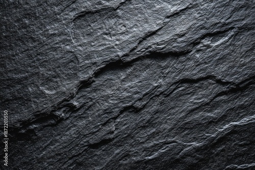Close-up of rough, textured dark grey slate rock, showing natural cracks and striations