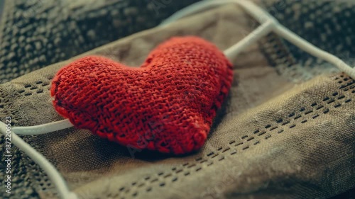 A small, handmade red heart-shaped gift box tied with string and ribbon, containing a sweet treat.