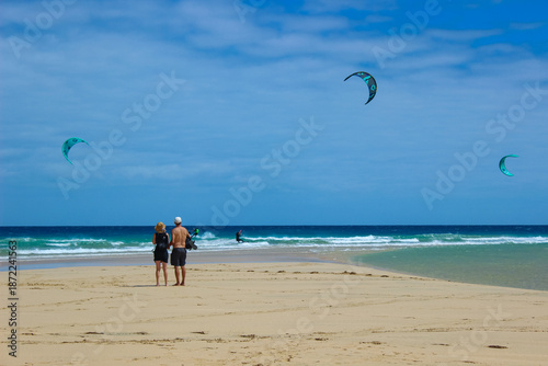 Couple Watching Kitesurfers on Fuerteventura Beach at Sunset