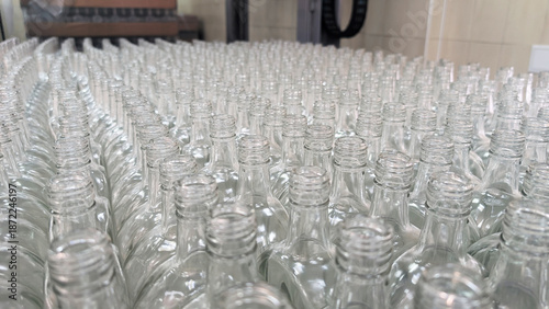 Empty glass bottles arranged on a production line in a large factory