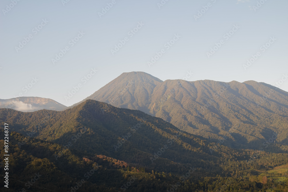 Fototapeta premium Mountain landscape in Indonesia with forested hills and clear sky copy space