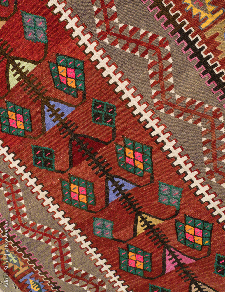 Fototapeta premium A close-up of a traditional Turkish carpet featuring intricate geometric patterns in red, beige, and accents of green and blue.