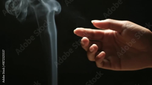 Hand Catches Smoke in Dark Background.