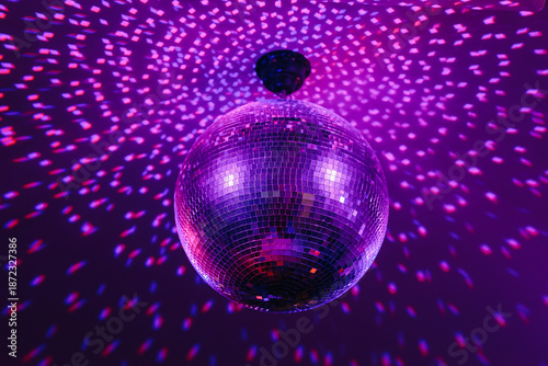 disco ball with mirror surface and bright rays, purple color, hanging on ceiling, night party background