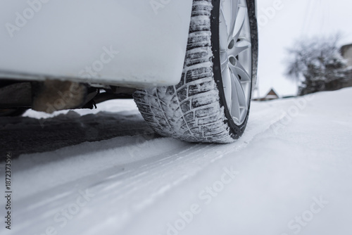 Tablou pe pânză Low-angle view of a car tire gripping a snow-covered road