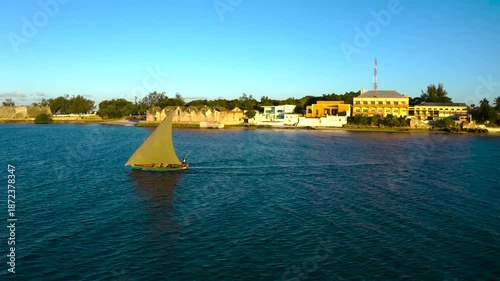 Aerial view of a dhow sailing on the shimmering sea, its sail catching the golden sunset light, creating a stunning contrast, Nampula, Mozambique.