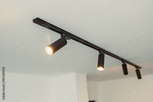 Tablou pe pânză Track lighting with adjustable spots in a modern space showing warm light illumi