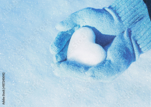 Hands in knitted gloves with heart of snow in winter day. Love concept. Valentine day background.