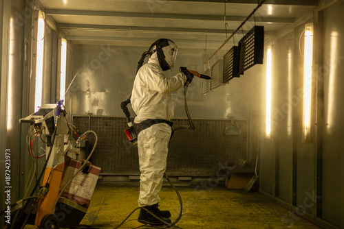 Industrial Powder Coating Process – Worker Spraying Metal Panels in Protective Suit