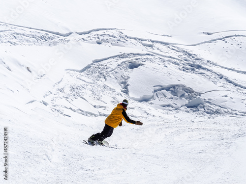 Rear view of a snowboarder wearing a yellow jacket at the Sierra Nevada ski resort (Granada, Spain) on a sunny winter morning