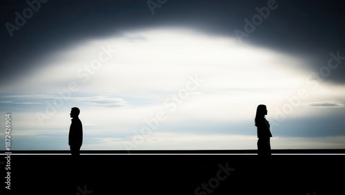 Isolated silhouetted man and woman, depicted in a powerful high-contrast conceptual photography style, standing far apart and facing away from each other across a stark horizon line, dramatically lit