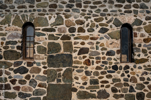 Two small rectangular windows built into a stone building. A window seen on church or monastery buildings.