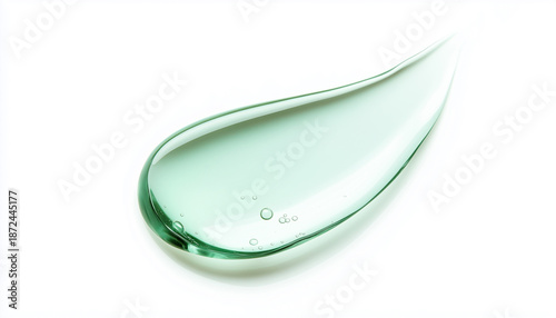 Clear light green cosmetic gel smear on white background. Liquid substance forms flowing texture. Isolated macro view