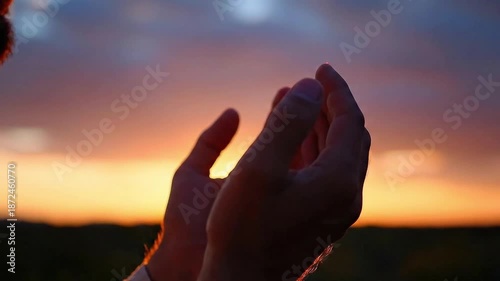 Silhouette of male hands raising, peaceful and sincere, praying and making Dua against dramatic sunset sky