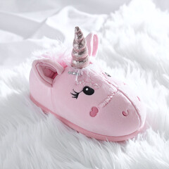 Adorable pink plush unicorn slipper with a glittery horn resting on fluffy white fur. Ideal for cozy home themes, magical sleepwear branding, and whimsical lifestyle photography.