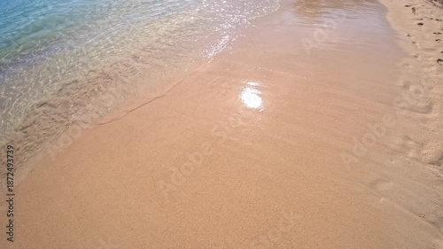PORTOCOLOM, MALLORCA, SPAIN - OCTOBER 25, 2025: Calm waves gently touch the golden sand, wide background shot. A peaceful sunny day at the beach in Mallorca, Spain. Can be used for slow-motion.