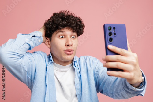 фотографія Shocked man reading unexpected phone notification in studio on pink background