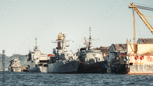 Quadro su tela Telephoto view of gray naval warship and auxiliary vessel moored at dockyard pie