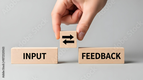 The hand places the block with arrows in the input feedback loop, which illustrates the importance of business communications and improvements.