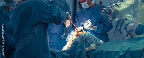 Surgeons employ a robotic surgical assistant during a knee replacement procedure, focusing on precise bone resections and soft tissue assessment