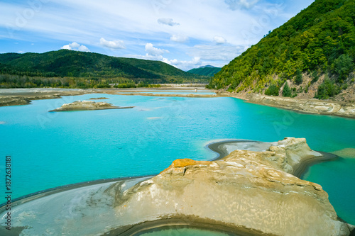 The effects of pollution on a natural habitat, featuring damaged terrain and pools of toxic water surrounded by lush hills.