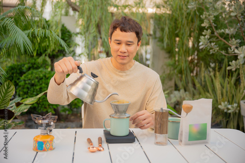 Slika na platnu Asian man happily drip coffee beans in him home garden.