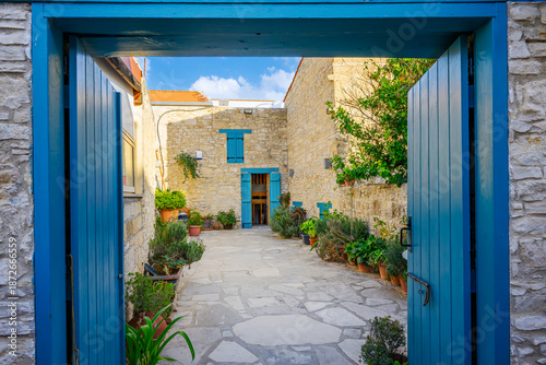 Fotografie Vibrant blue double doors lead to a stone garden courtyard in the medieval mountain village of Omodos, on the Mediterranean island of Cyprus