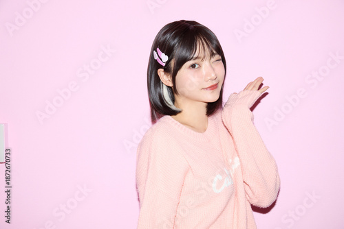 ピンク背景でキュートなポーズをする若い女性のポートレート