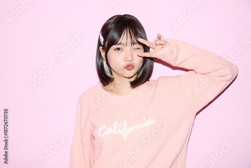Naklejka ピンク背景でキュートなポーズをする若い女性のポートレート