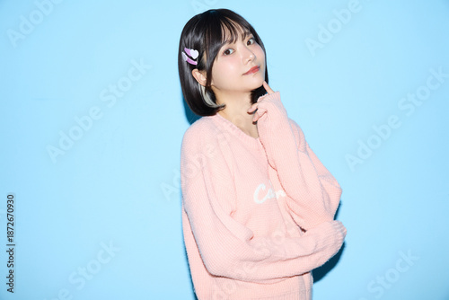 ブルー背景でキュートなポーズをする若い女性のポートレート