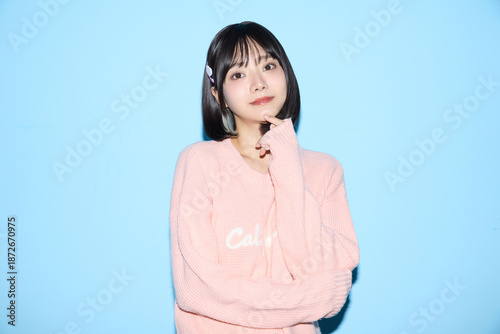 ブルー背景でキュートなポーズをする若い女性のポートレート