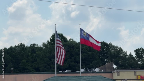 DOLLY SLOW MOTION SHOT - The Georgia state flag is waving along with the national flag of the United States of America in Norcross, Georgia, USA.