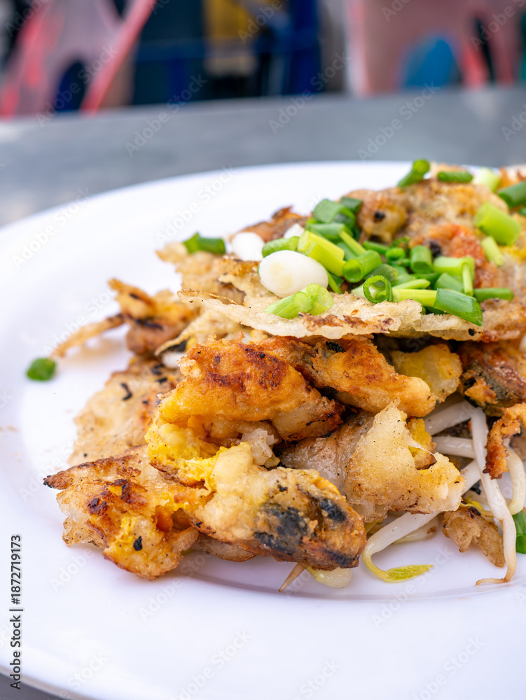 Fototapeta premium Crispy Thai Oyster Omelette (Hoi Tod) served with fresh bean sprouts and spring onions on a white plate