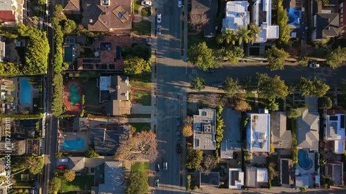 Cinematic top down view of Los Angeles California capturing residential street scene with detached homes, green trees, sidewalks and suburban atmosphere