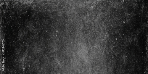 A grainy monochromatic image showing a dark textured surface with subtle variations in tone and contrast