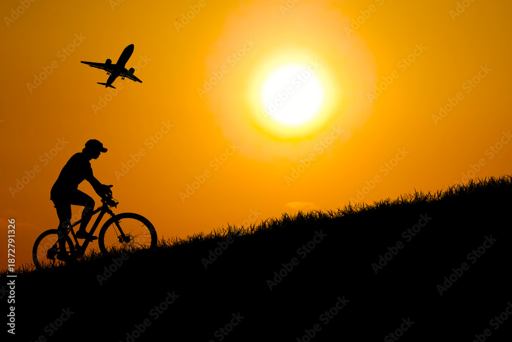 custom made wallpaper toronto digitalSilhouette of a person cycling during a sunset with a plane in the sky. The warm sunlight creates a breathtaking scene of travel and adventure