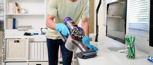 Cuadro en lienzo Asian man with handheld vacuum cleaning on Desk in home office.