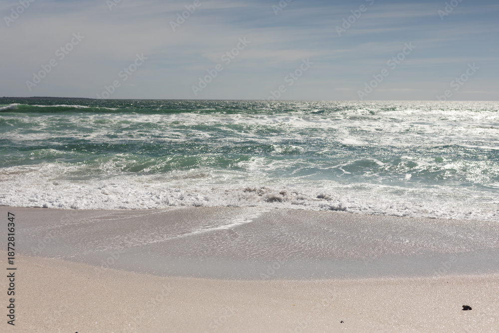 Obraz premium Waves crashing on shore at beach against sky during sunny day