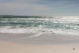 Waves crashing on shore at beach against sky during sunny day