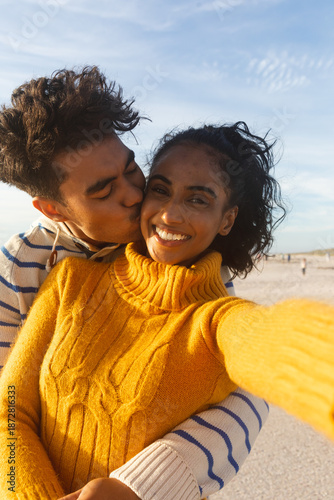 Fotografia Portrait of smiling woman taking selfie of boyfriend hugging and kissing on chee