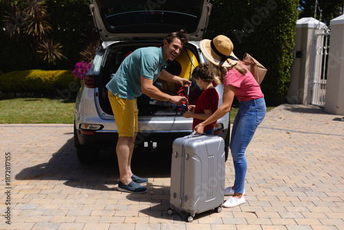 Happy caucasian family putting their luggage in car on sunny day