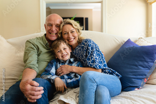 Obraz na płótnie Portrait of caucasian grandparents and grandson smiling while sitting together o