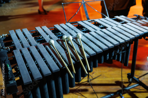 Fotografie A vibraphone with resting mallets stands on a warmly lit stage, its metal bars a