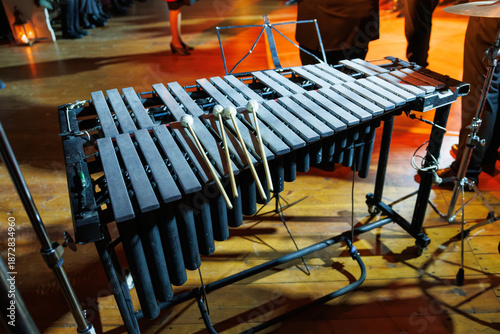 Fotografie A vibraphone with resting mallets stands on a warmly lit stage, its metal bars a