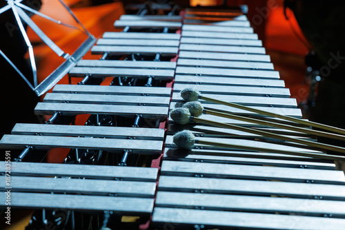 фотографія A vibraphone rests on stage under warm lights, mallets placed across metal bars,