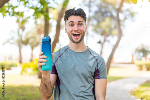 Photography Young handsome sport man with a bottle of water at outdoors with surprise and sh