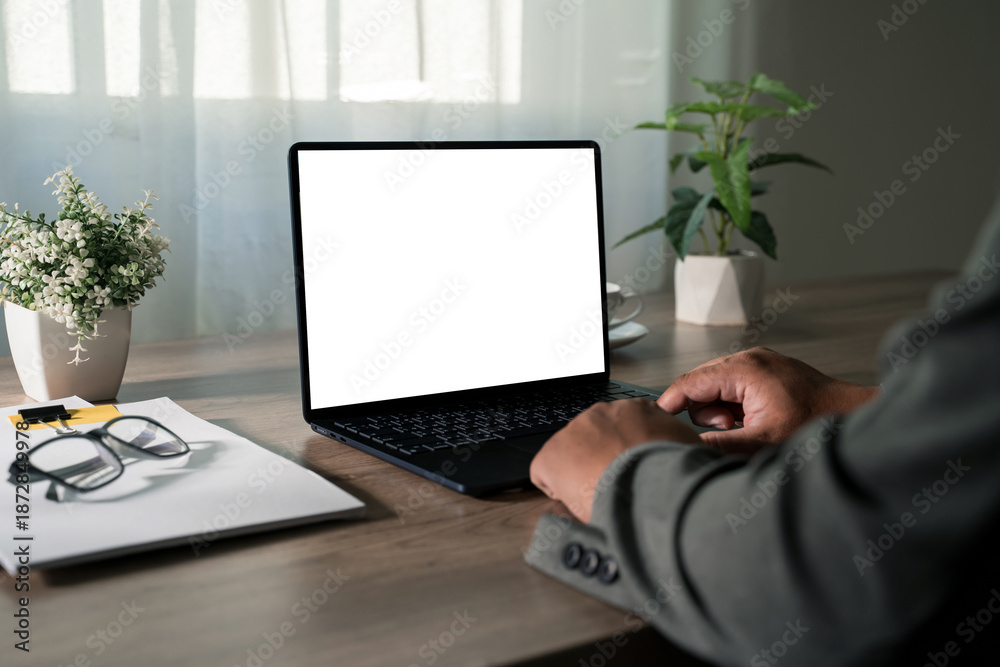 Fototapeta premium Remote work concept with modern laptop, coffee mug and office supplies arranged neatly on wooden home office desk near window, creating a clean productive workspace for freelancers and small business.