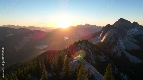 Golden sunrise illuminates a majestic mountain range, casting long shadows over rugged peaks and evergreen forests