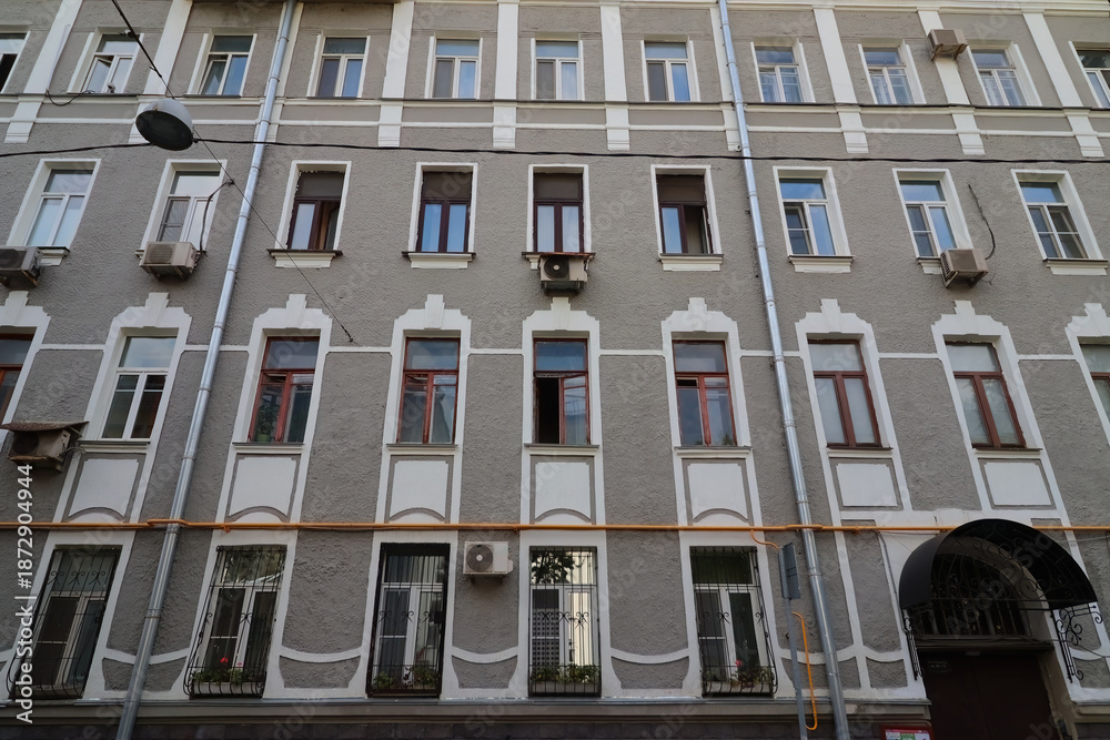 Obraz premium Facade of a multi-story building with a classic architectural style. Exterior is painted in light grey tone with white decorative elements