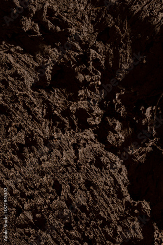 Foto Gros plan sur une texture de terre sombre et humide, illustrant un sol naturel brut avec un relief organique en environnement extérieur